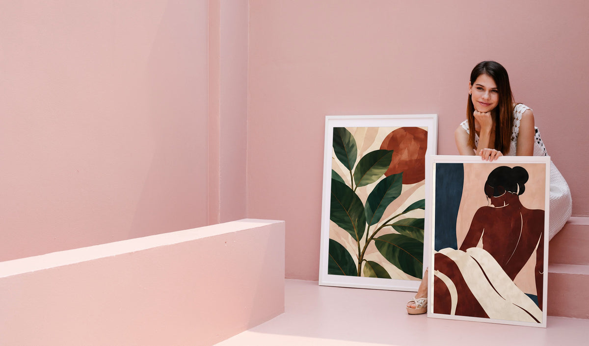 A woman leaning on two framed prints against a pink wall