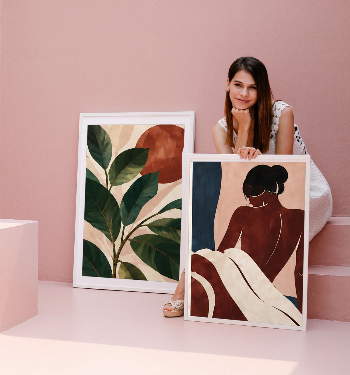A woman leaning on two framed prints against a pink wall